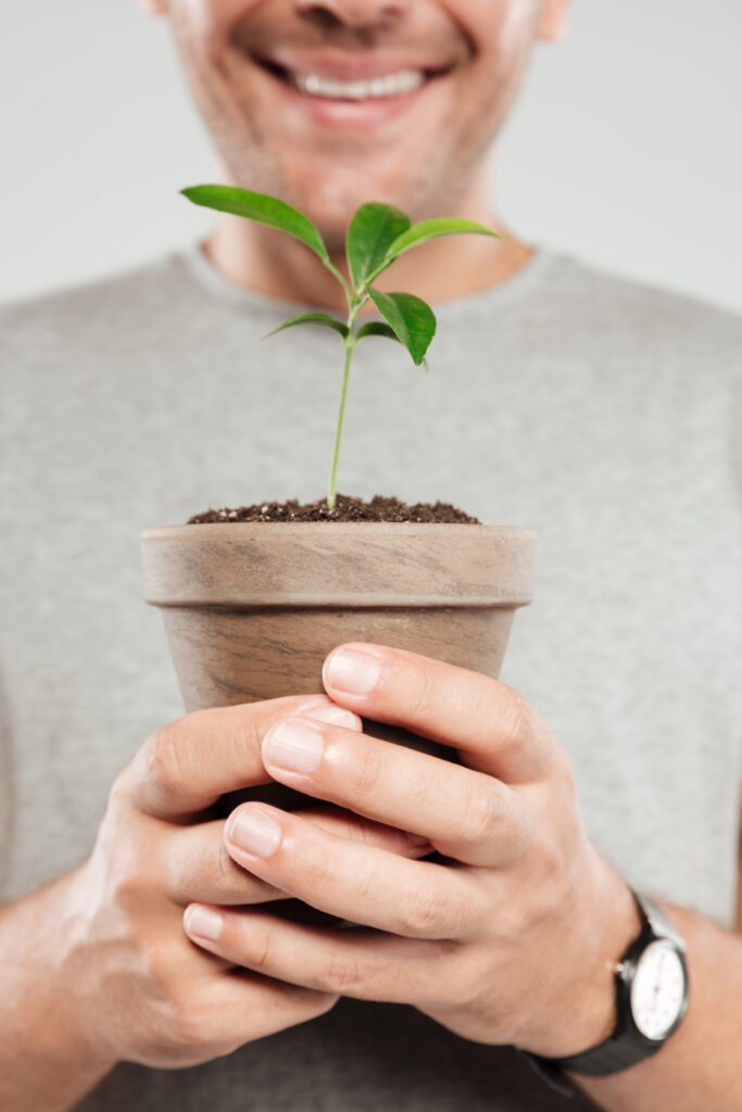 smiling man holding plant.