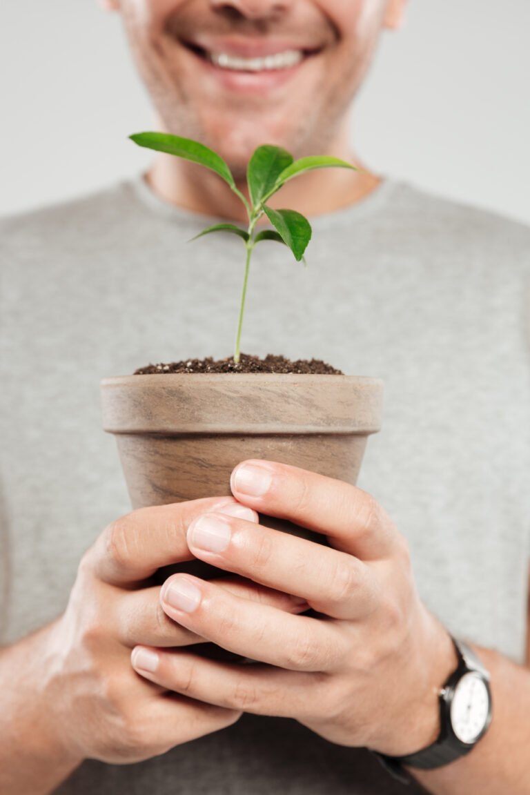 smiling man holding plant.